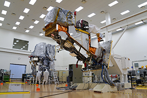 People working in a clean manufacturing setting with large equipment elevated.