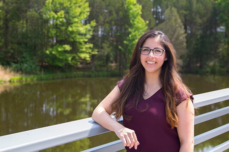 Woman smiles poses outside behind lake