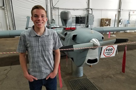 Young man standing in front of small airplane