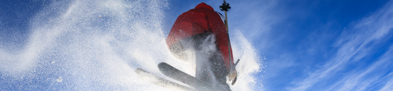 Skiier in mid-air against blue sky and clouds