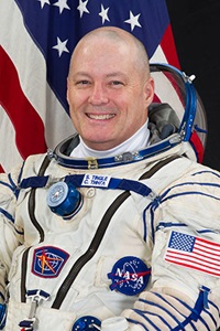 Northrop Grumman Heritage Company Intern Scott Tingle NASA Astronaut Bald man wearing astronaut uniform in front of American Flag