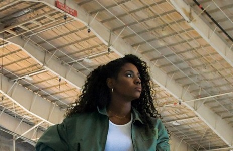 African American Female standing in Hangar with Large plane