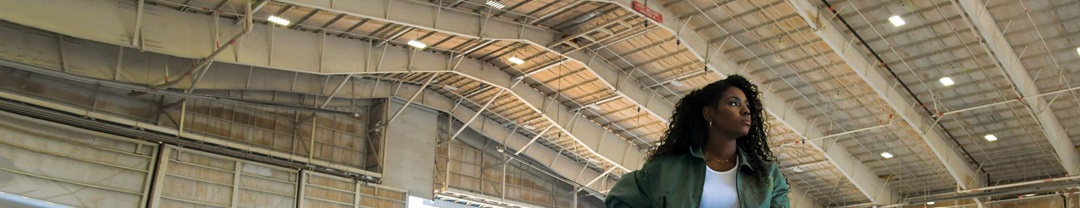 African American Female standing in Hangar with Large plane