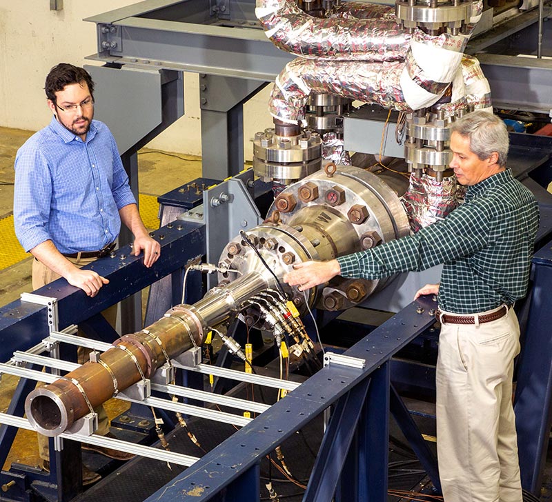 two men standing over rocket propulsion system