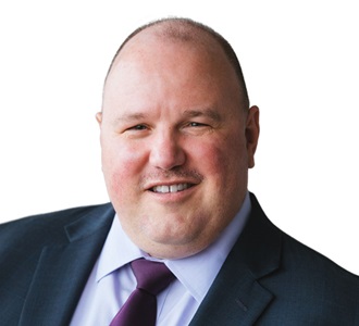 a white man in a suit smiles at the camera