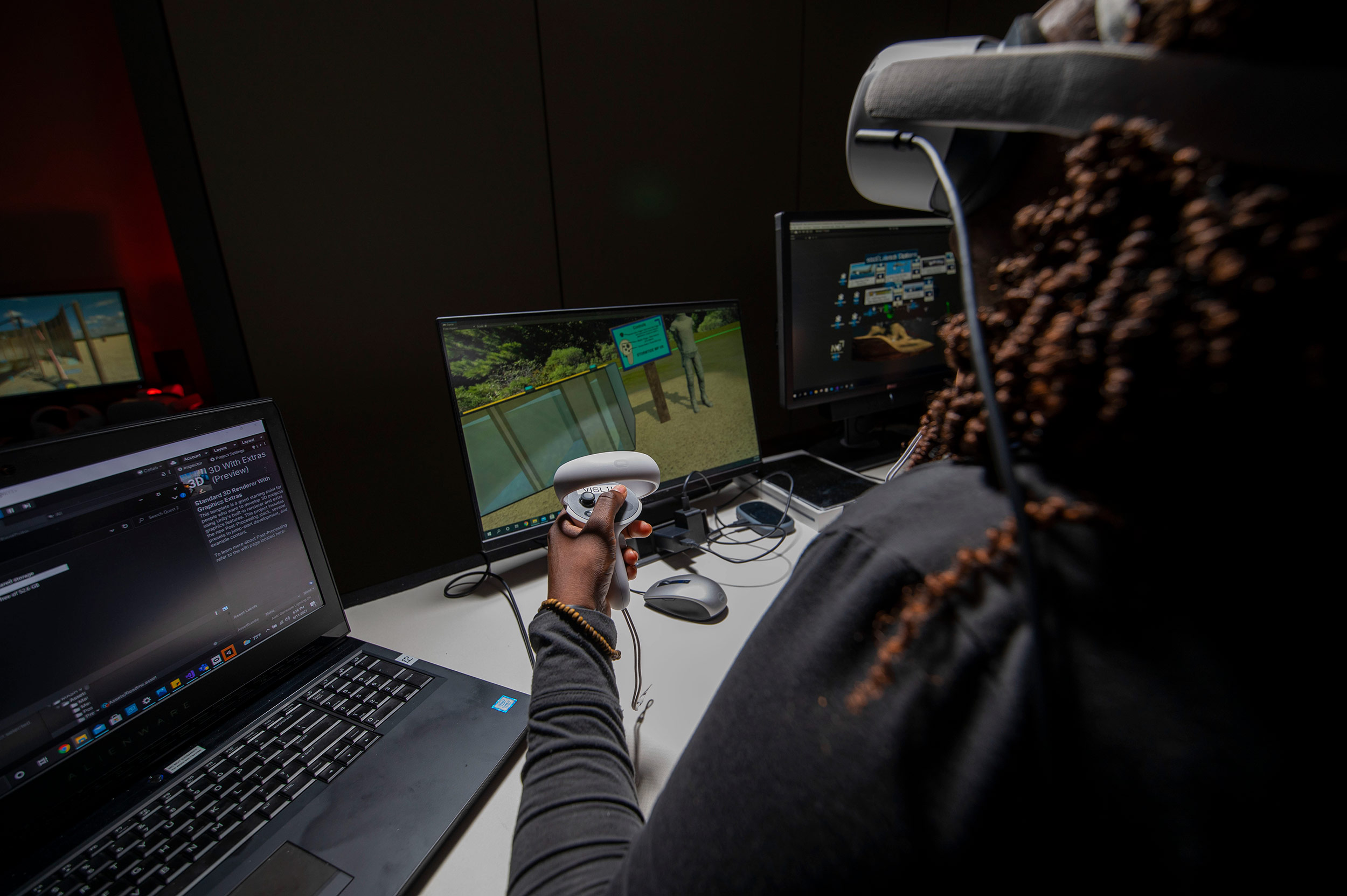 ar-vr-formulas-for-success-3 A woman sits at a computer wearing a virtual reality headset and holding a game controller