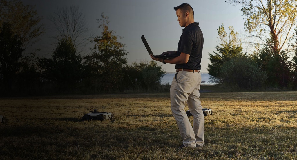 Asian American man holding laptop to control remote vehicles