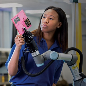 black woman working with robot arm holding microchip