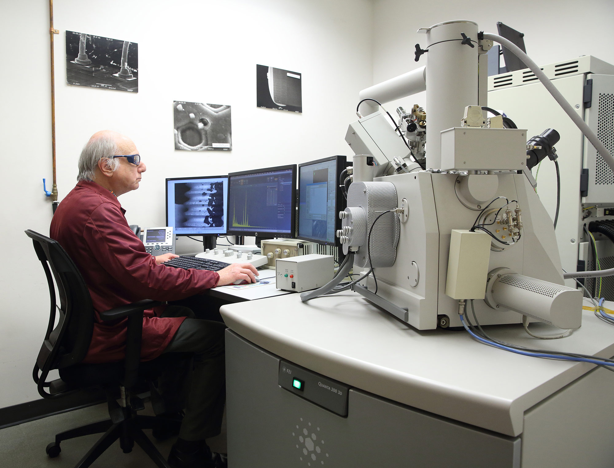 a man in a maroon lab coat works on a computer