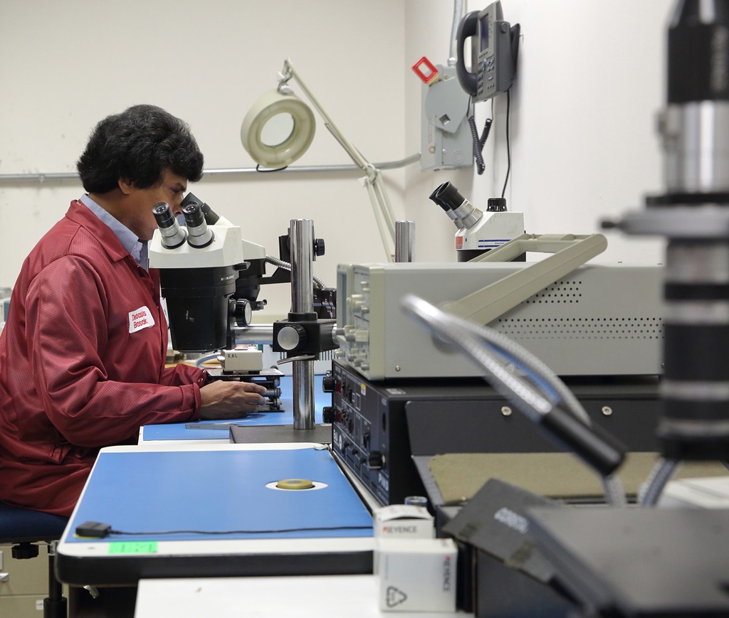 a man in a maroon lab coat looks into a telescope