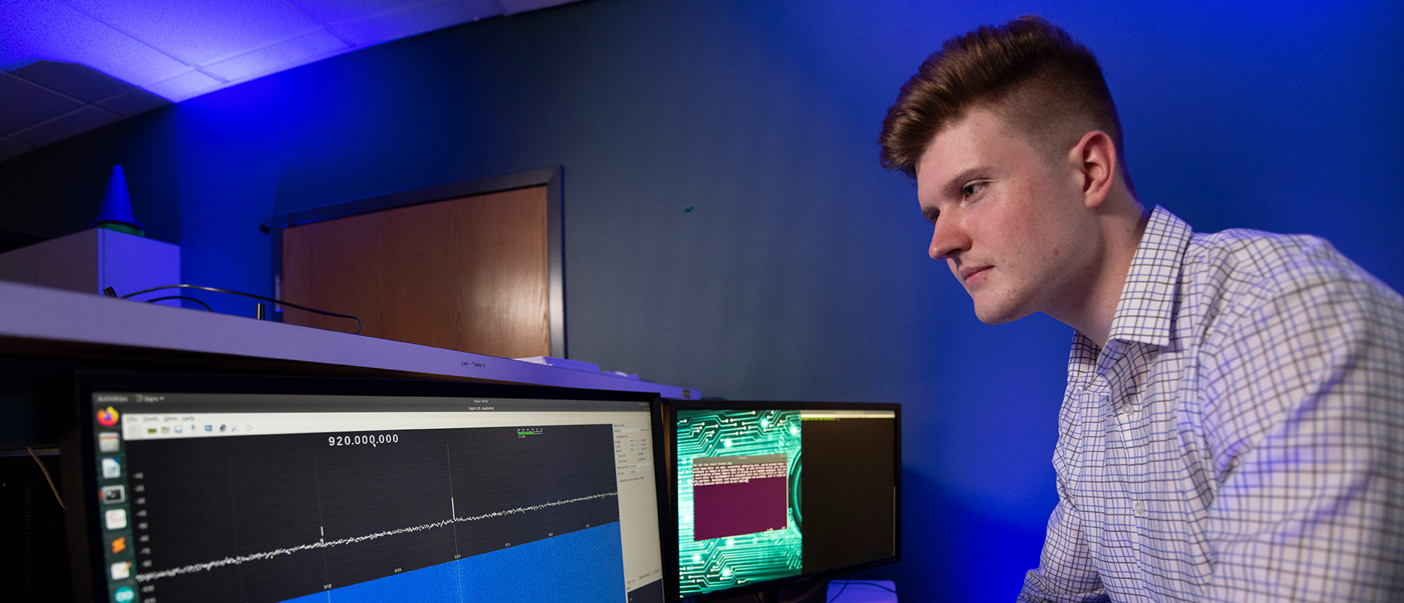 a man stands in front of two computer monitors