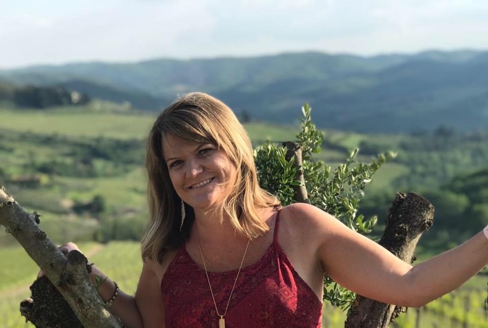 White woman stands smiling in nature