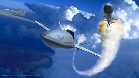 An aircraft flies through clouds next to a missile with smoke trail behind it.