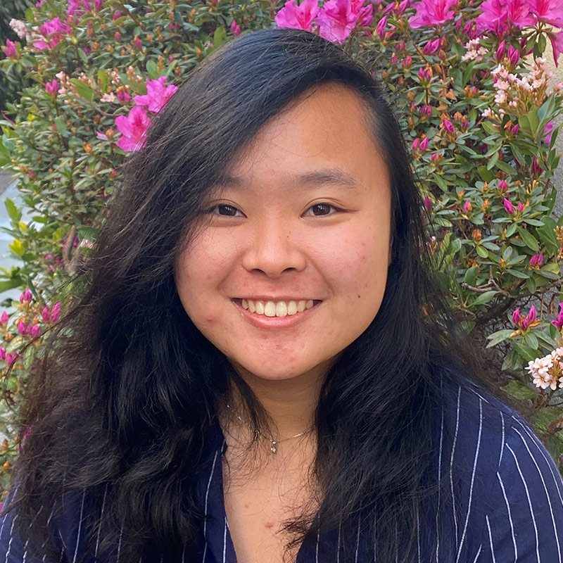 asian female smiling in front of flowers