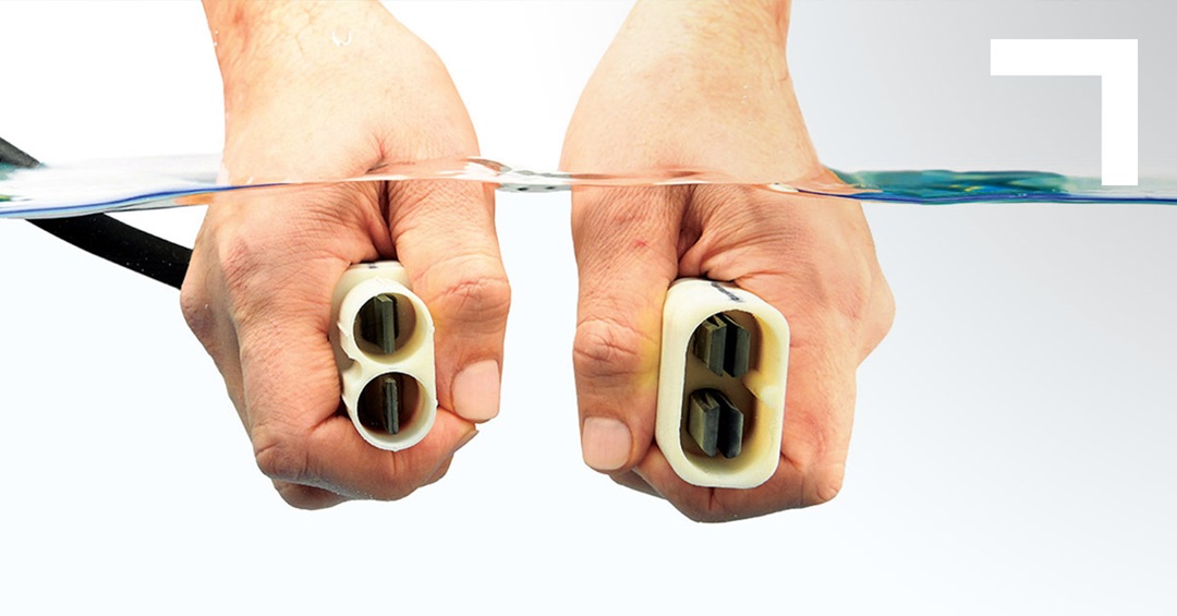 hands holding electrical connector under water