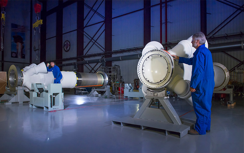 two men in blue coats work on rocket