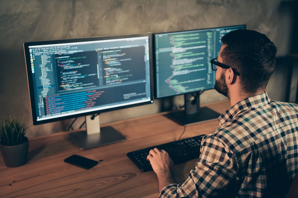 Man wearing glasses looking at computer monitors