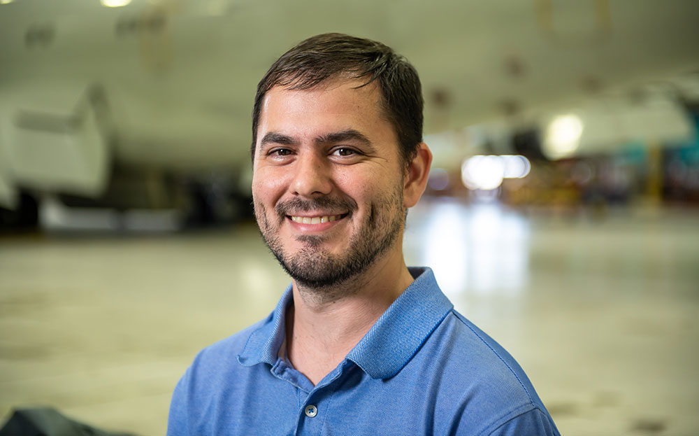 white male headshot in front of military aircraft