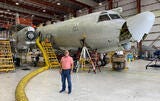 man standing in front of plane in hangar