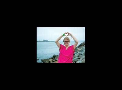 woman in pink shirt with hands making a heart