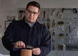 White man wearing safety goggles works in workshop