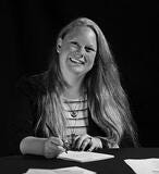 woman smiling while writing a note