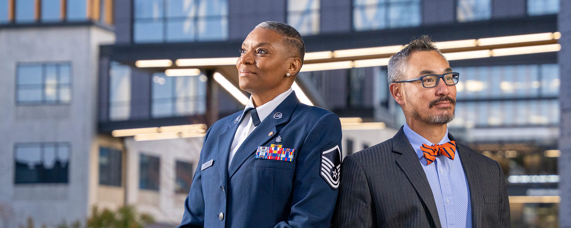 woman in uniform and man in bow tie in front of building