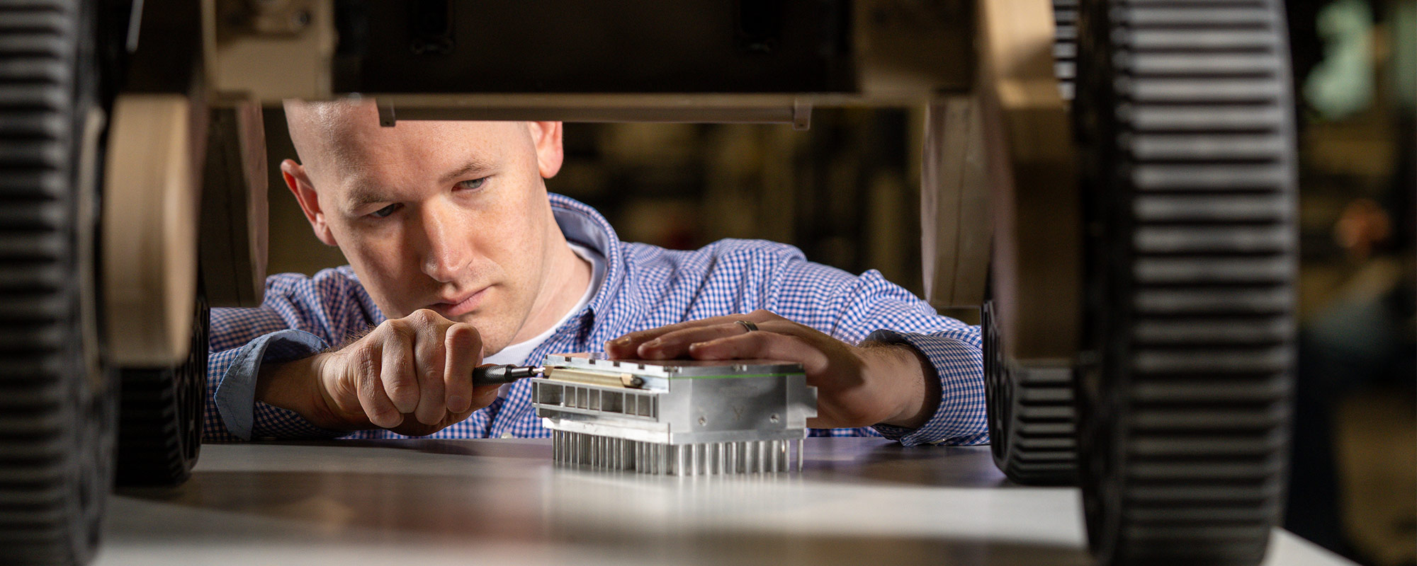 man working on electronics under a drone vehicle