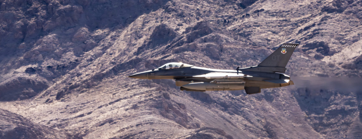 F-16 fighter jet flying over mountains