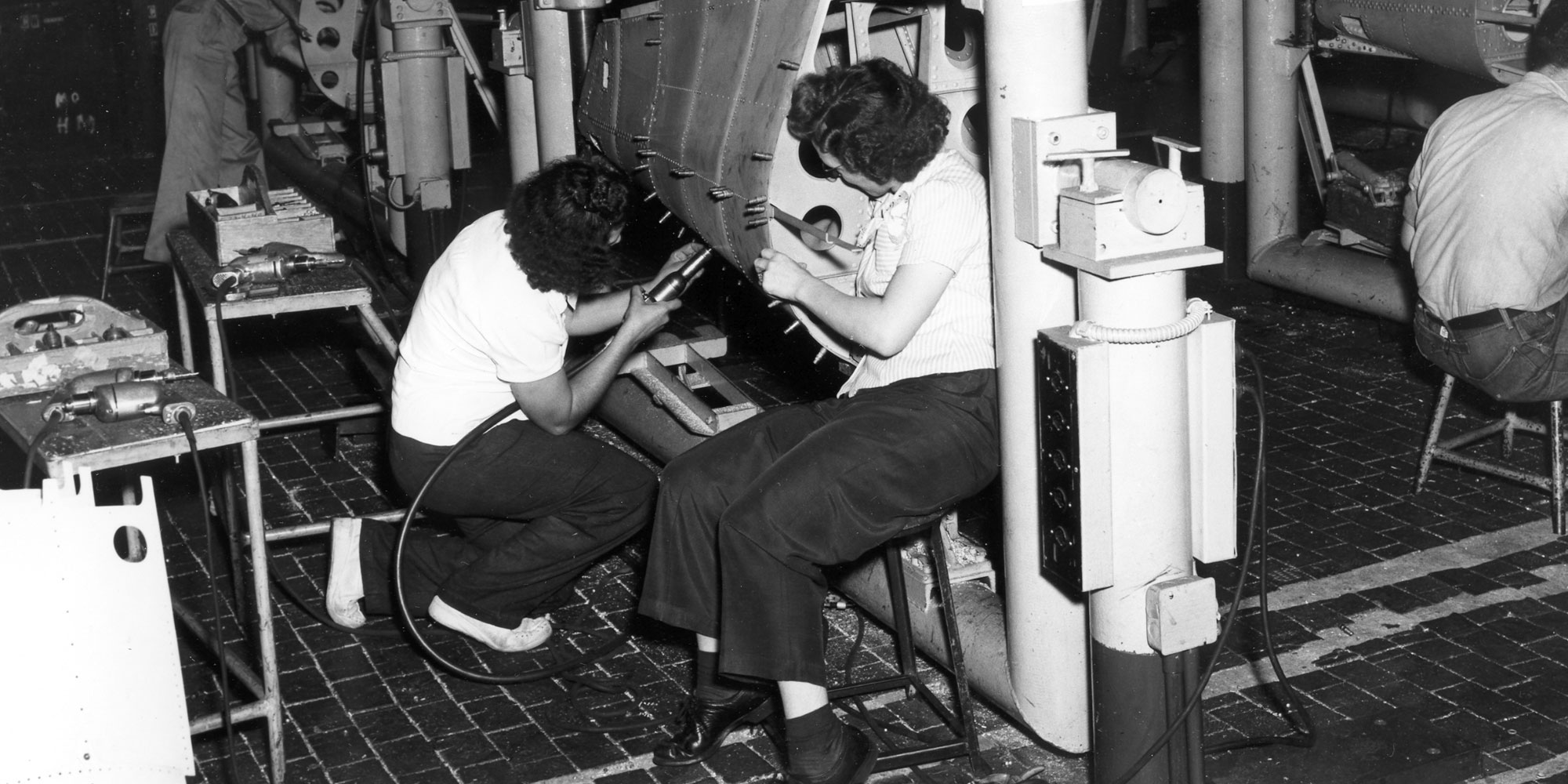 Black and White photo of women working on world war 2 airplane.