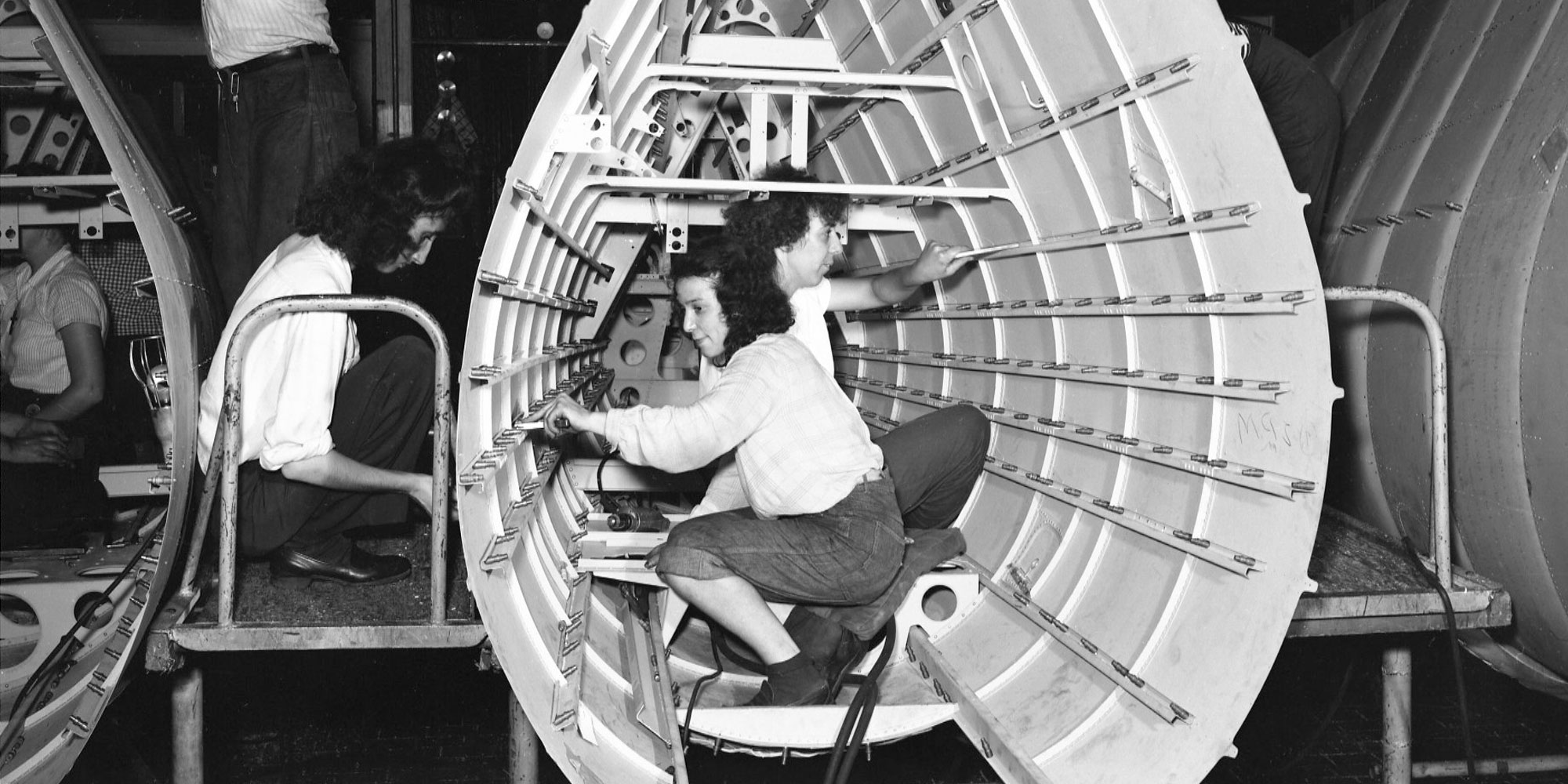 Black and White photo of women working on world war 2 airplane.