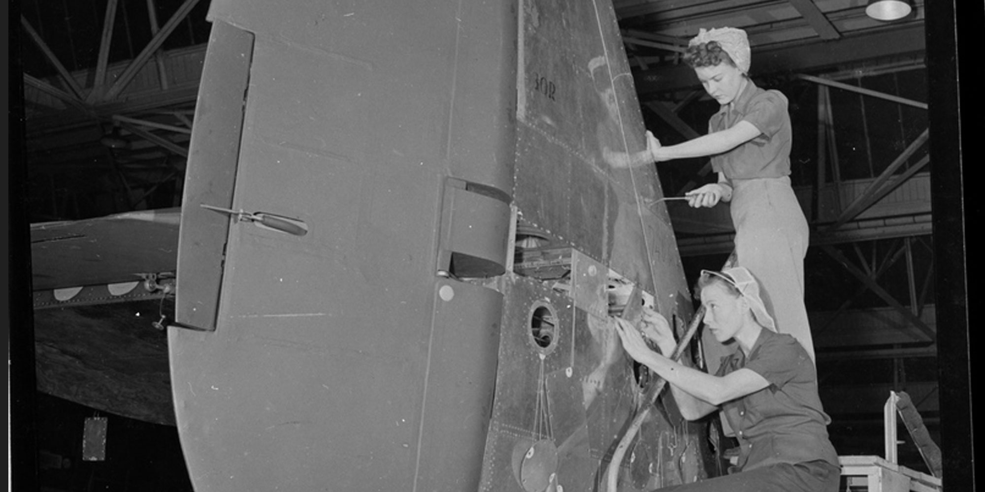 Two women work on an airplane in factory during world war 2