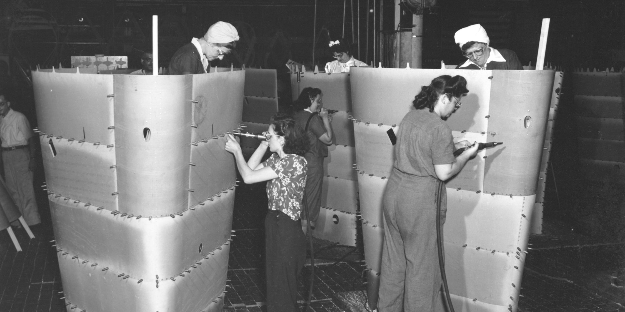 Black and White photo of women working on world war 2 airplane.