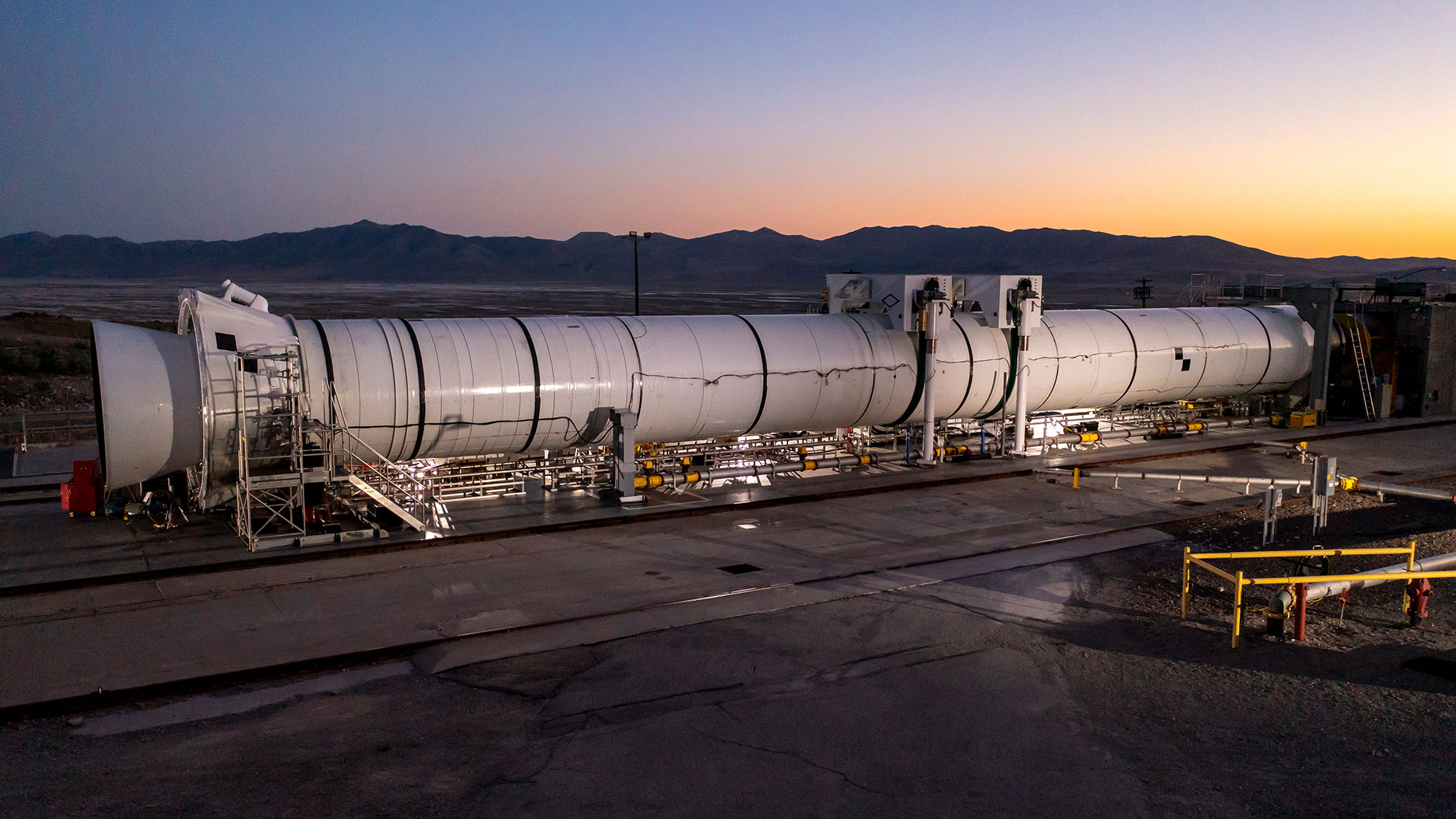 Artemis I – Flight Support Booster-2 Test: A full-scale SLS motor prepares for testing at the Northrop Grumman Promontory, Utah, facility rocket laying flat on test site at sunset
