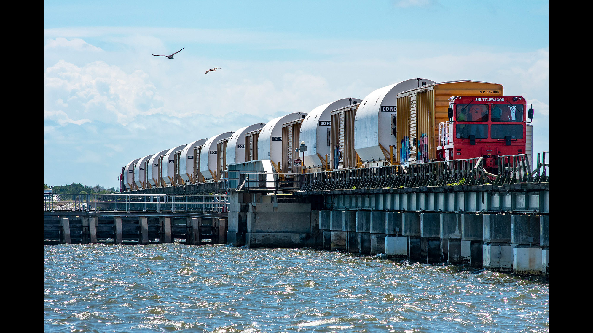 Artemis I Space Launch System rocket on train over bridge