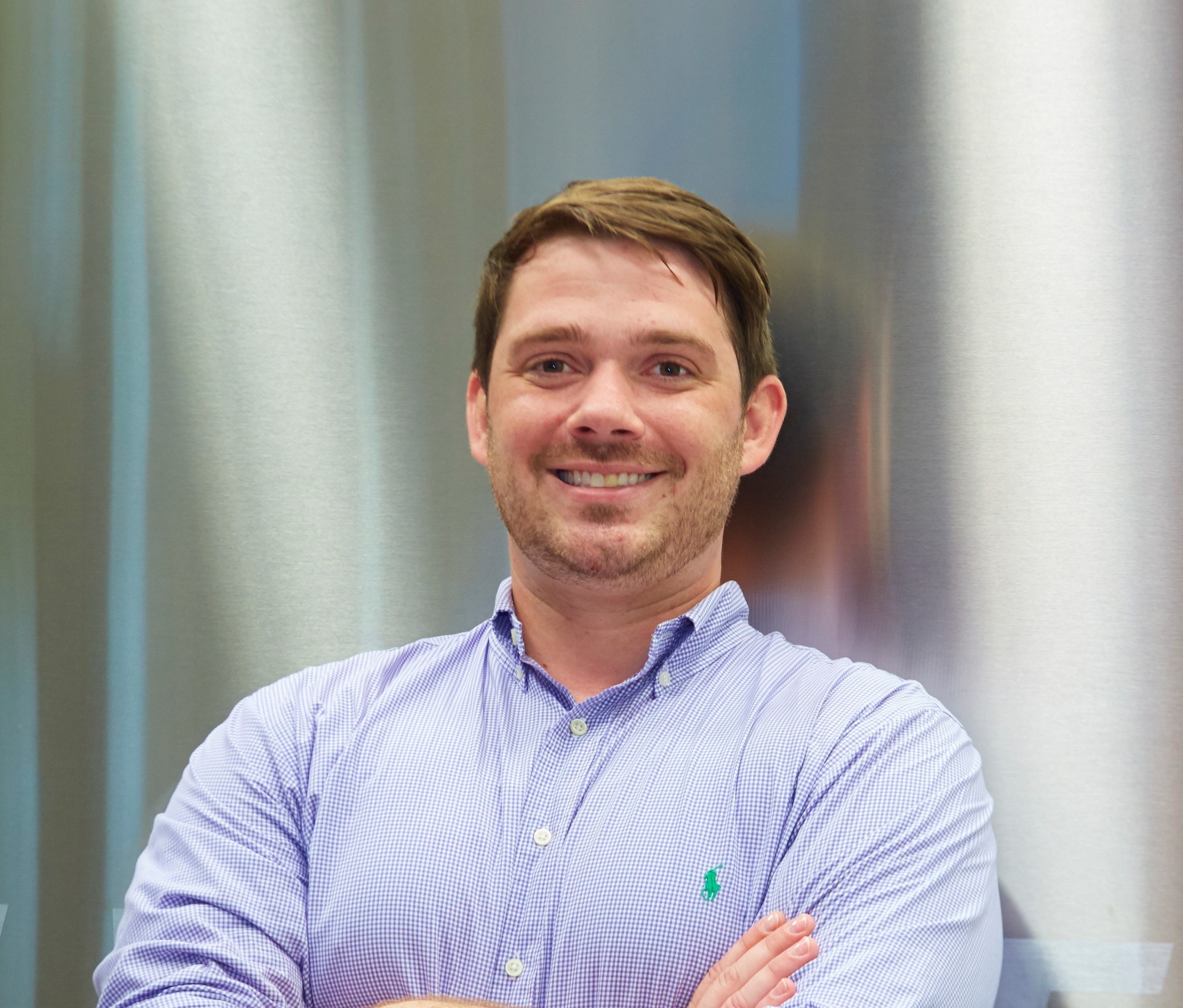 Caucasian male poses smiling with arms crossed